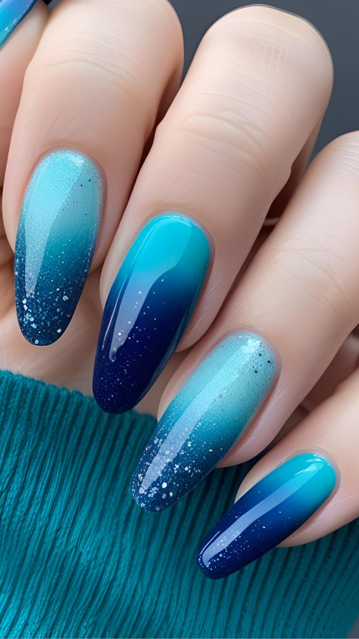 Blue aura nails with gradient ombré and sparkly finish on long oval tips.