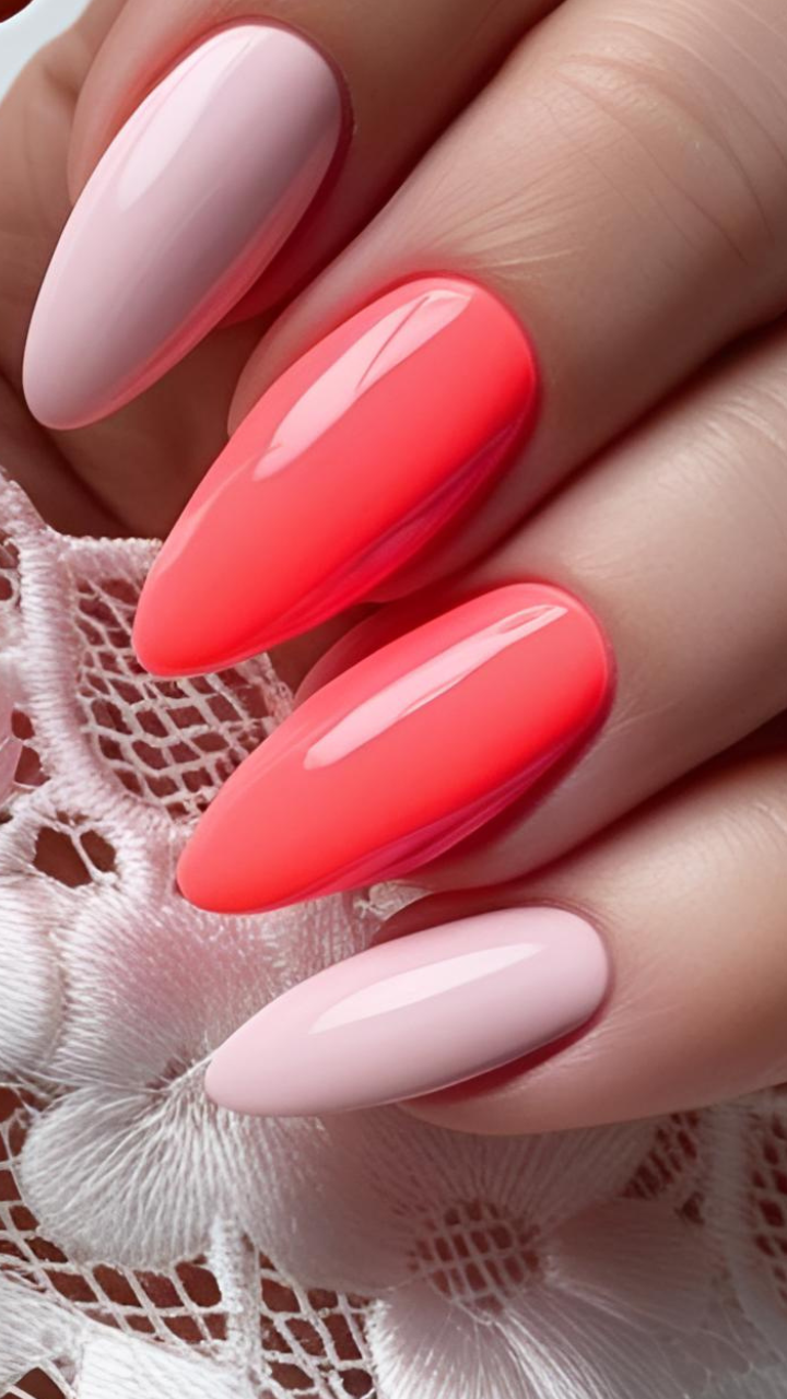 Almond-shaped nails in a glossy coral and blush pink gradient design on lace fabric.